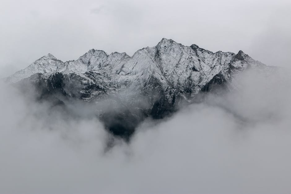 A breathtaking view of snow-covered mountain peaks surrounded by dense fog